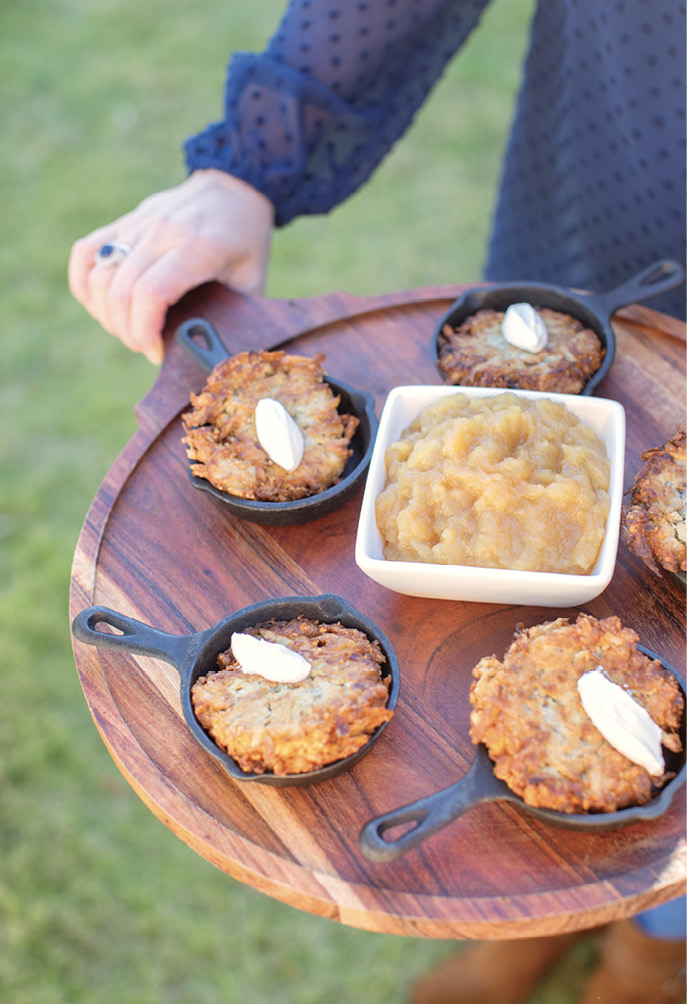 Potato latkes in mini cast iron skillets are served with applesauce.