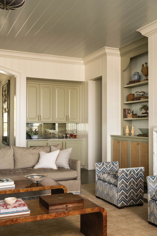 A built-in wet bar and cabinets surrounding the fireplace were inspired by late 20th-century Chippendale cabinets and designed to feel timeless with a subtle sense of whimsy.