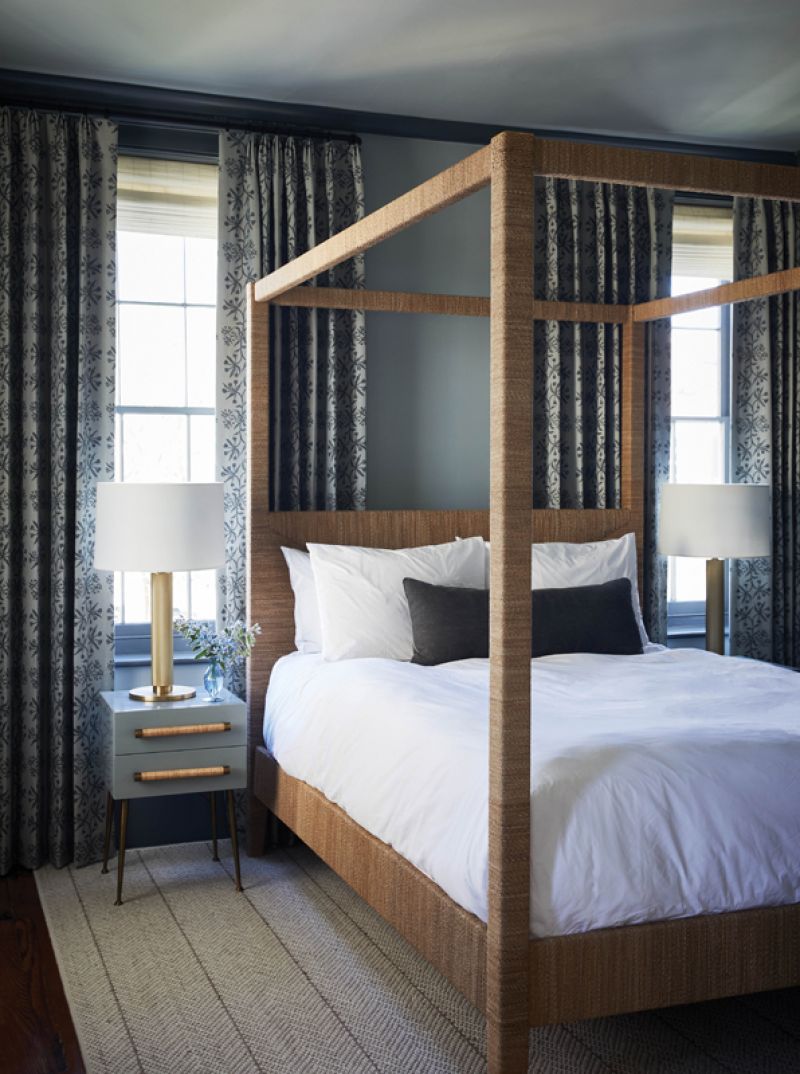 Organic Vibes: The second floor’s other bedroom belongs to one of the couple’s children. Here, a Serena &amp; Lily “Hughes” four-poster bed, wrapped in organic lampakanay sea grass, pops against the gray floral drapes in Kerry Joyce “Best Buds” fabric and the gray walls and ceiling.