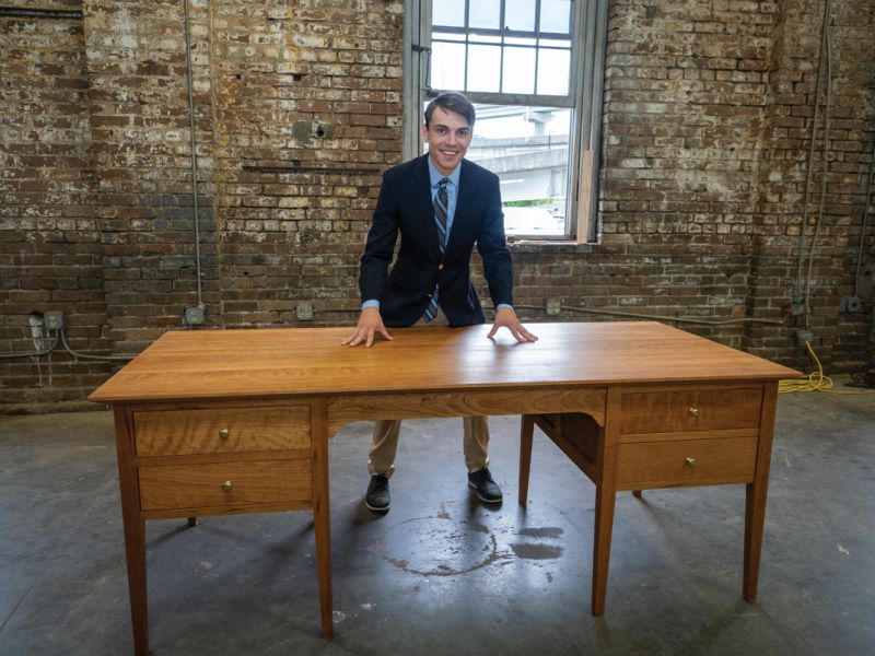 Jacob Nyman with his cherry office desk inspired by Stickley, Colleton House, and Thos. Moser.