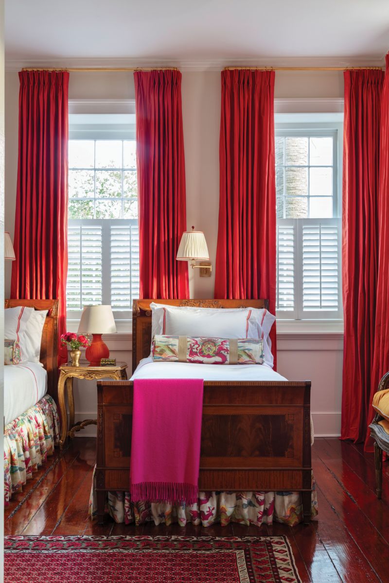 Rosy Outlook: The guest bedroom features bold red drapes made from a Christian Fischbacher fabric, Matouk bedding with custom embroidery, and reading lights from Visual Comfort on walls painted in Benjamin Moore “Opaline.”