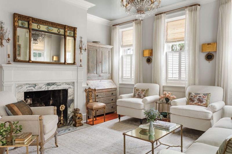 Over a decade later, the couple was able to retire to the circa-1797, Federalist-style home, prompting a thoughtful interior redesign—including this elegant drawing room—that marries modern living with exquisite antiques and vintage furnishings, such as the Maison Charles brass sunflower wall sconces and Maison Jansen mirrored coffee table from Karl Kemp.