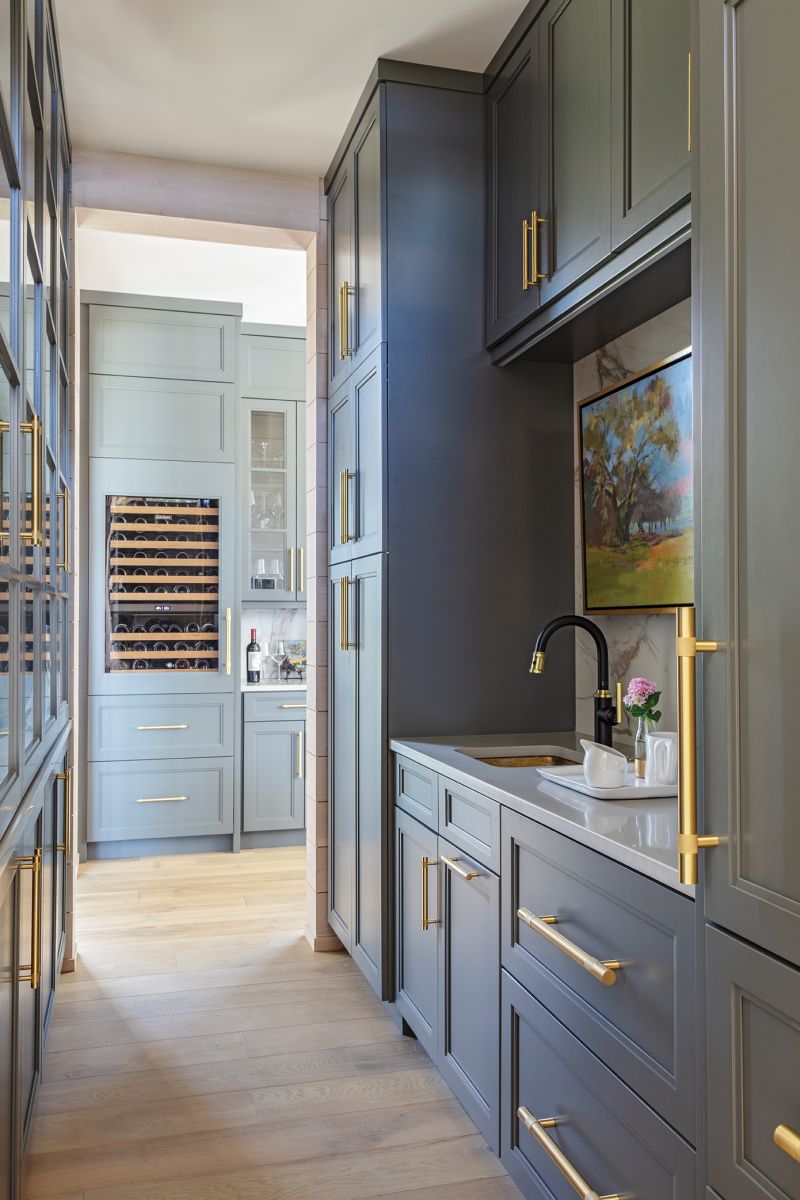 In the butler’s pantry, brass pulls from Bird Hardware accentuate stepped Shaker cabinets painted in Sherwin Williams “Grizzle Gray.”