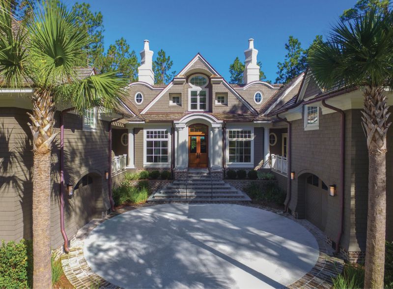 WELCOME HOME: An entry courtyard, flanked by one-car garages topped with private guest quarters, became the stately starting point for the overall design concept. (Left) An open floor plan leads to a back terrace and pool area, where an endless marsh vista awaits.