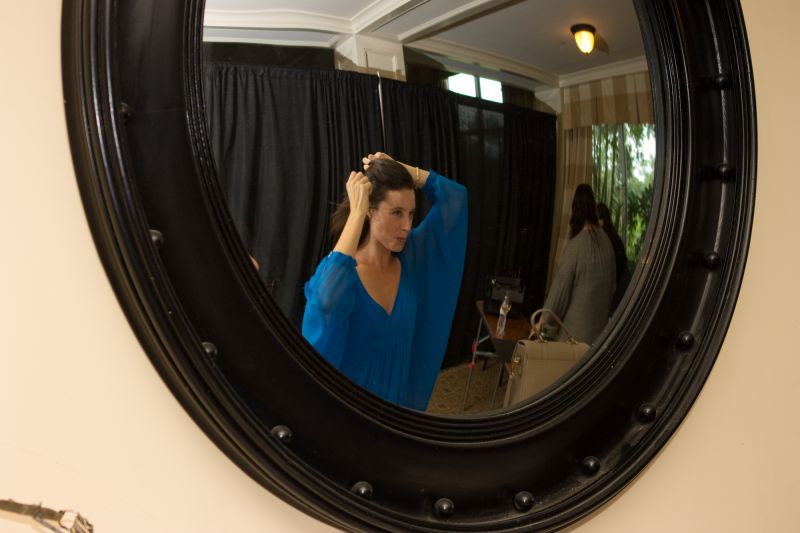 Models backstage prepared to showcase shoes and clothes on the runway during a fashion show.