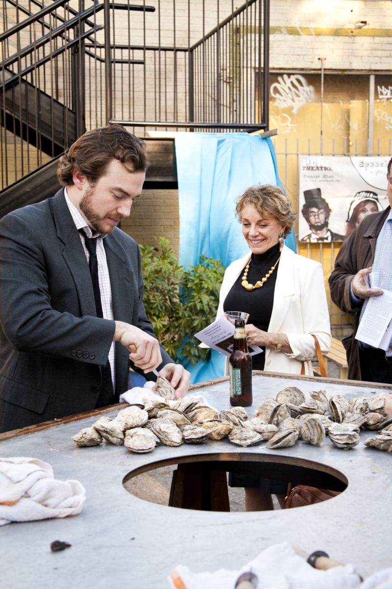 Jake Bantel demonstrating his shucking skills to Linda Esposito