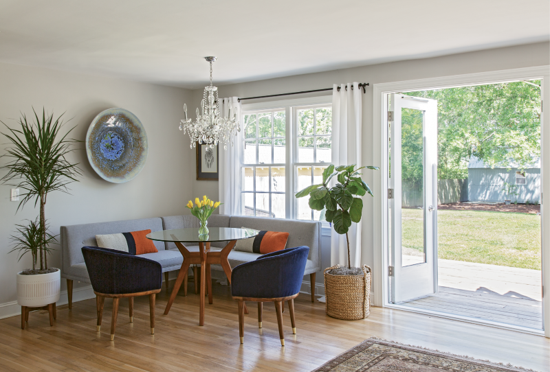 GATHER ’ROUND: Up to seven people can fit comfortably in the West Elm-clad dining nook. When hosting a large group, Rachel simply swaps this glass tabletop out for a larger version. Pottery Barn drapes, a chandelier from Carolina Lanterns &amp; Lighting, plants from Hyams, and a bowl hand-thrown by Louisiana artist Craig McMillan finish off the space.