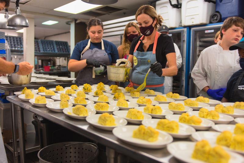 Little chefs Chloe Farkouh and Claudia Hassell assist Carrie Morey in plating vegan biscuits with curry.