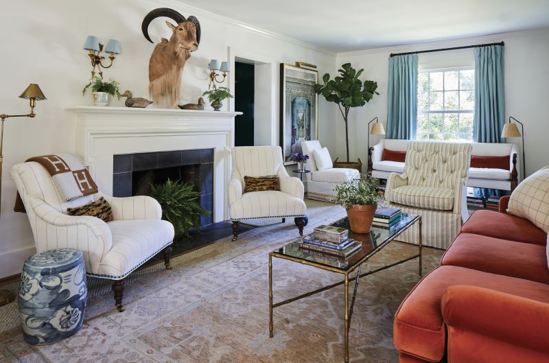 From Room to Room: The Miles Redd for Schumacher wallpaper adorning the dining room largely informed the palette of the rest of the home, including the living room, where neutral walls, rugs, and upholstery provide a calm and cozy base for pops of persimmon (via the velvet sofa) and dusty blue (à la custom drapes and vintage sconces).