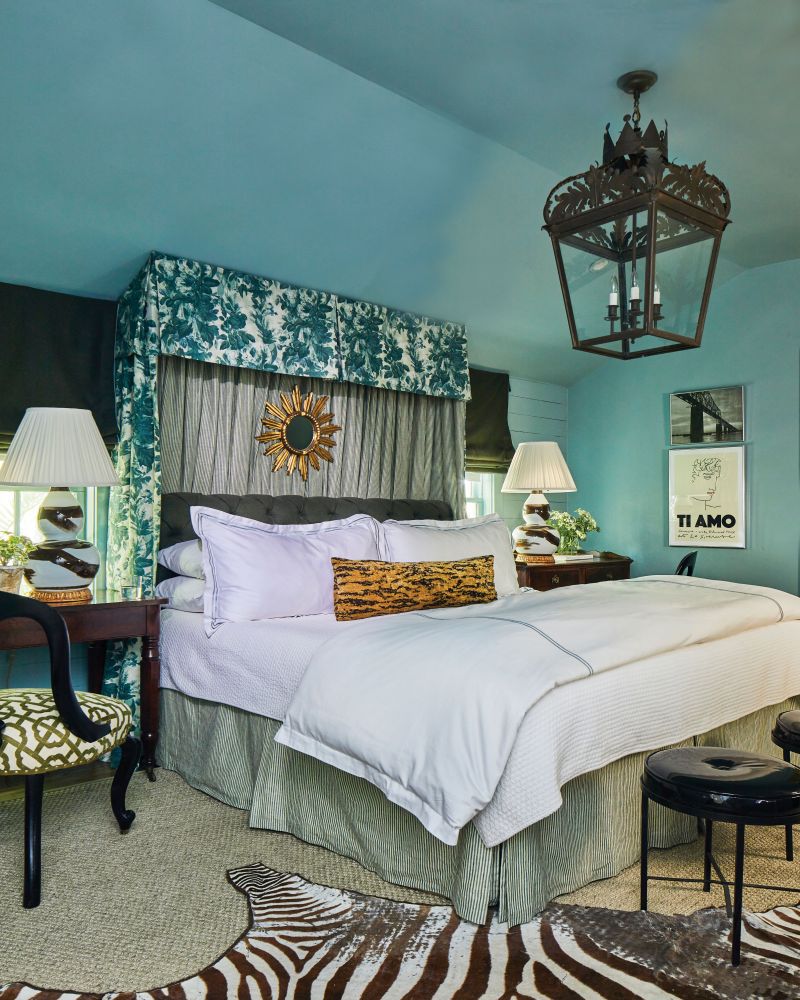 Lush Layers: In the primary bedroom, Cooper mixed chintz and men’s suiting fabric for a traditional bed canopy, which helped address the room’s odd angles. The oversize lantern, which originally hung outside a downtown home, was sourced at Wynsum Antiques.