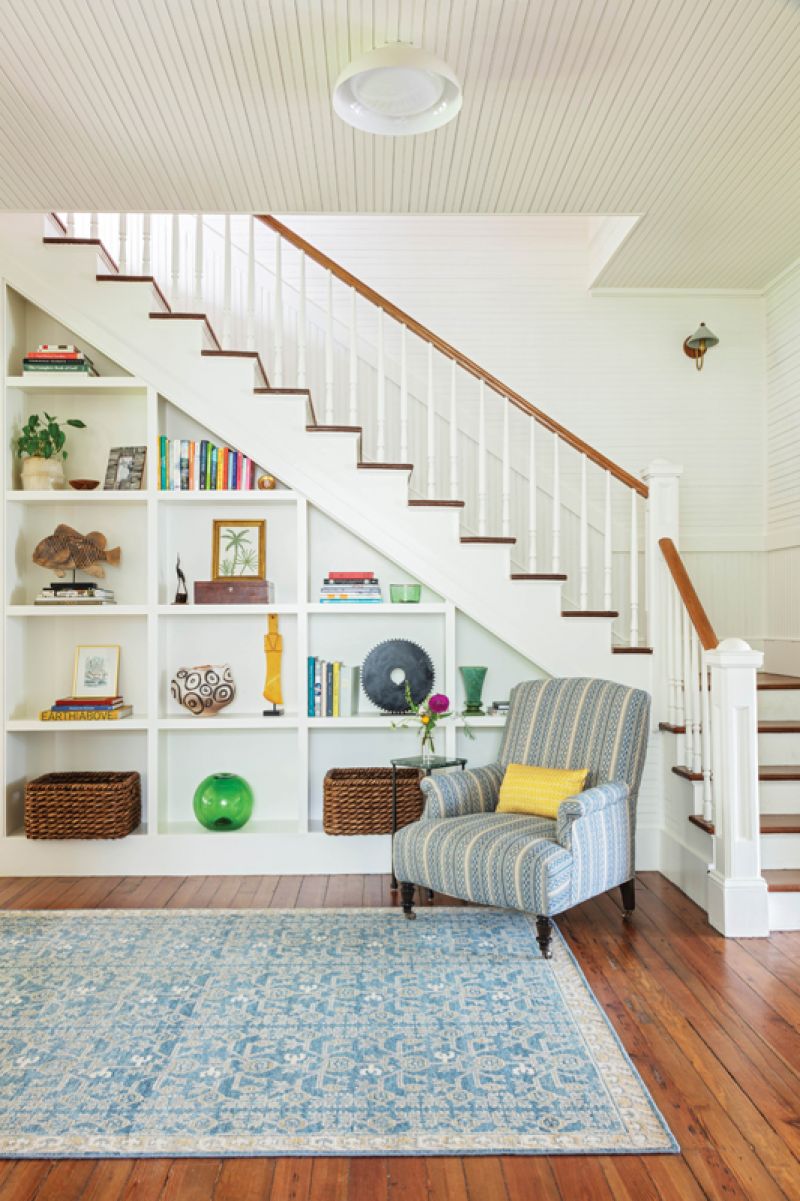 At the other end, a club chair wrapped in Susan Deliss fabric sits in the nook created by the staircase. Here, Sarah-Hamlin Hastings designed built-in shelving to showcase art and decorative items.