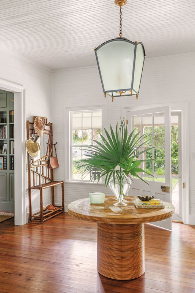 An antique lantern over a vintage Crespi-style rattan table creates a focal point in the wide entry hall.