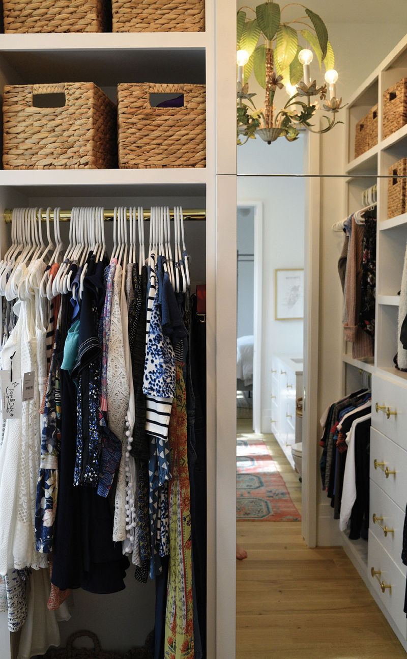 The large, walk-in closet—complete with built-in drawers and a stacked washing machine and dryer—gives Ella plenty of storage space and helps her stay organized. A whimsical vintage toleware palm tree chandelier lends charm and character.