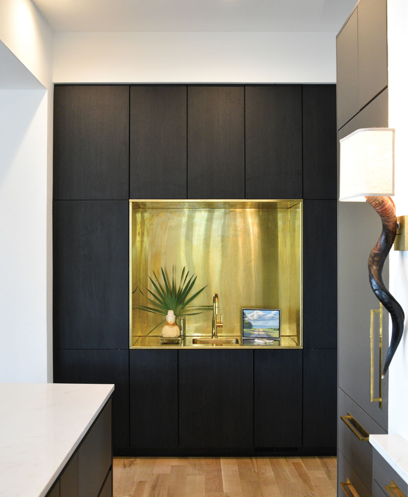 This unlacquered brass wet bar, fabricated by Mount Pleasant metalworker Jon Mako, adds a warming graphic element to the dramatic kitchen.