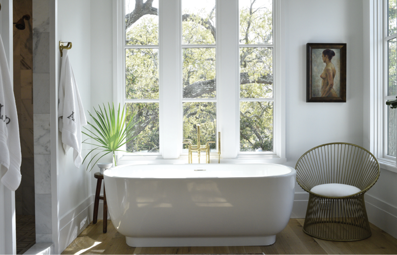 BATHING BEAUTY: It may look sleek and minimal, but this Laura Kirar freestanding bathtub from Kallista weighs more than 500 pounds. Installing it into Alix’s personal oasis “required a few good men,” she says. Brass fixtures from Moluf’s, a chair from Celadon Home, and a painting from Antiques of South Windermere pop in the all-white space.