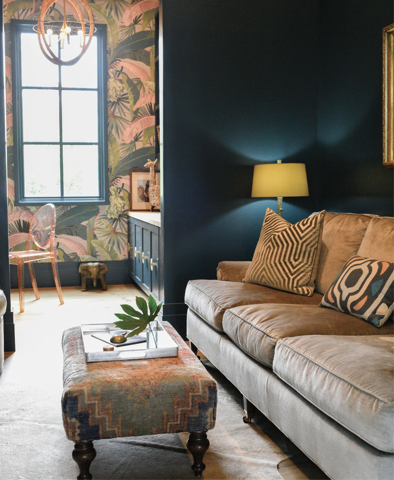 The interior’s largely subdued palette gets flipped on its head in this sumptuous sitting room and office nook. A bold, banana leaf-themed wallpaper by Mokum complements the rich teal walls painted in Sherwin Williams’s “High Battery.” A velvet sofa from Acquisitions Interiors and a custom vintage Turkish oushak ottoman are plush accents.