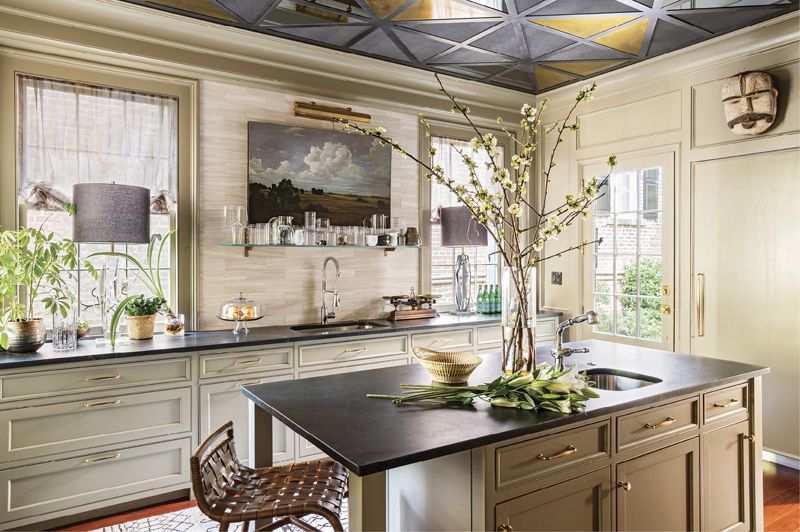 HEART OF THE HOME: The paneled kitchen (painted Benjamin Moore’s “Tavern Gray”) is laid out in zones. The far wall (adorned by a pastoral piece by Elizabeth Foster and a pair of Kate Spade lamps) is for prep, the island holds Michael’s baking tools, and the opposite wall (not pictured) is where he cooks.