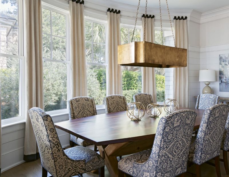 DINNER WITH A VIEW: The home’s formal dining room embraces the outdoors, courtesy of a large wall of windows carefully curved to capture the view of a small olive grove. The custom black walnut dining table, handmade by John Grisanti of Redwood Lumber Company in New York State, curves to the exact contour of the outer wall. A Gabby chandelier and Bernhardt chairs bring a sense of grandeur to the room.