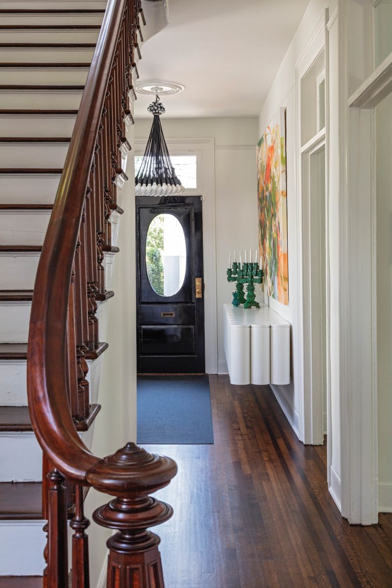 The mahogany newel post, shaped like a lighthouse, harkens to the city’s port heritage, while the front door, painted a deep Dutch black, connects visually to the kitchen beyond.