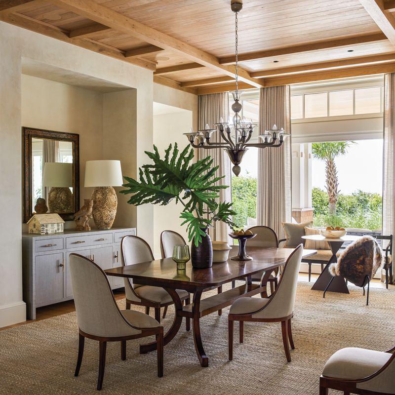 A New Classics walnut dining table surrounded by silk and linen upholstered chairs from Dessin Fournir centers the dining room and is illuminated by an antique Italian chandelier.