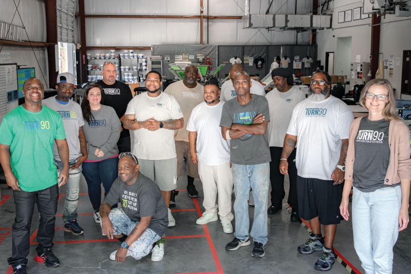 Turn90 founder Amy Barch (far right) with some of  her team at the program’s Columbia facility, including (from left) Terrance Ferrell, Deon Nowell, Sarah Brown, Joseph Smith, Melvin Bell, Ahmon Stewart, Billy Bullock, Lorenzo Strong, Aulzue Fields, Mark Roberts, Frederick Miles, and Jimmy Brown.