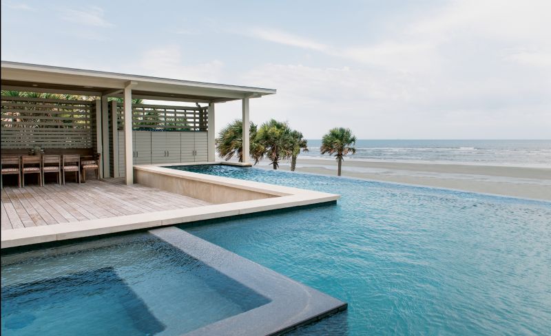 An elevated deck of garapa, a durable Brazilian hardwood, and a zero-edge pool are nested into the house, offering amazing views of the Atlantic.