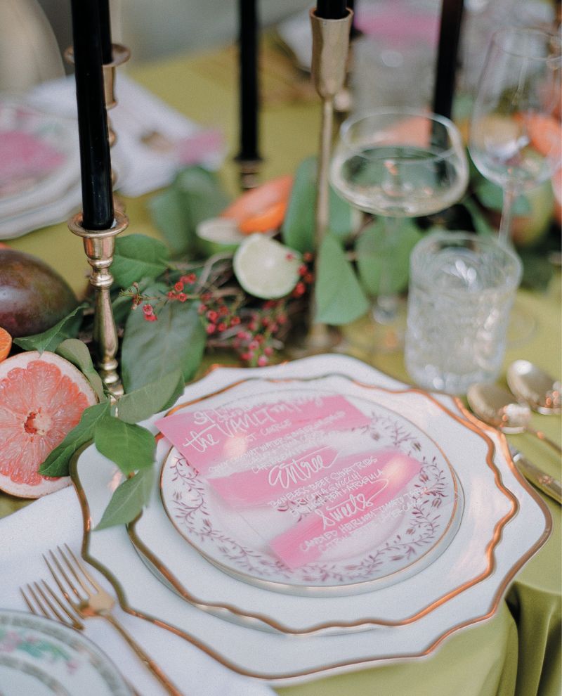 Each place setting of classic white and gold china chargers and dinner plates was topped with a uniquely patterned salad plate, as well as hand-painted acrylic menu cards by Mary Ruth Miller.